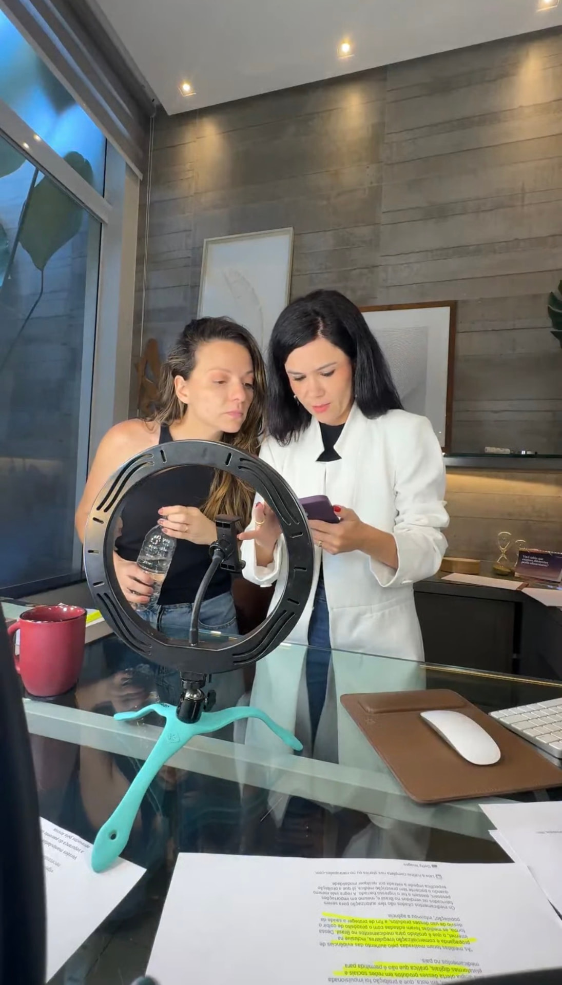Giuliane Mendes e Dra. Tassiane Alvarenga trabalhando juntas com ring light e celular no consultório